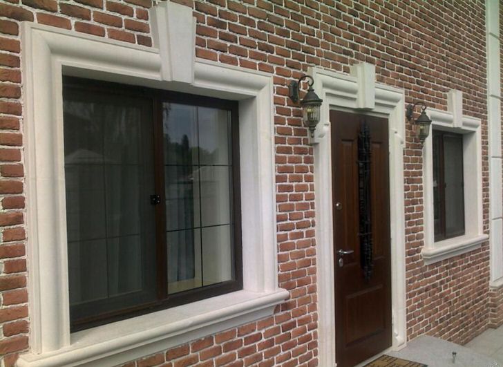 Кирпичная кладка органично сочетается с фасадной лепниной, обрамляющей оконные и дверные проемы.